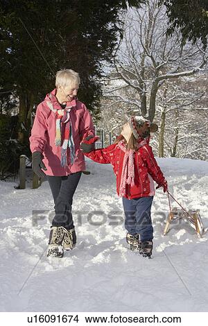 Picture - Young Girl With Grandmother Pulling Sledge Through Snowy Landscape. Fotosearch