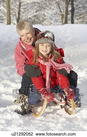 Stock Image - Young Girl With Grandmother Riding On Sledge In Snowy Landscape. Fotosearch