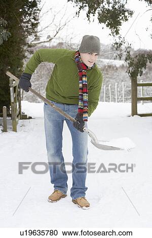 Stock Image - Young Man Clearing Snow From Drive. Fotosearch