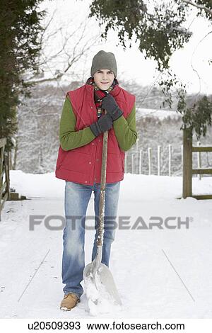 Stock Image - Young Man Clearing Snow From Drive. Fotosearch