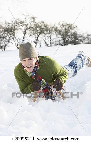 Stock Image - Young Man Riding On Sledge In Snowy Landscape. Fotosearch