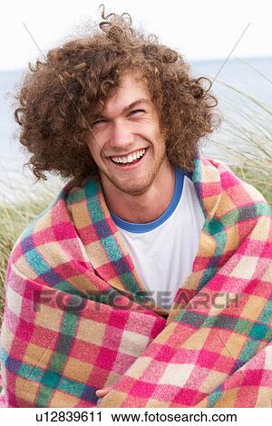 Stock Image - Young Man Standing In Sand Dunes Wrapped In Blanket. Fotosearch