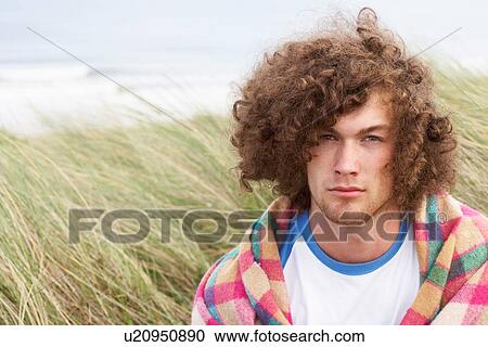 Stock Image - Young Man Standing In Sand Dunes Wrapped In Blanket. Fotosearch