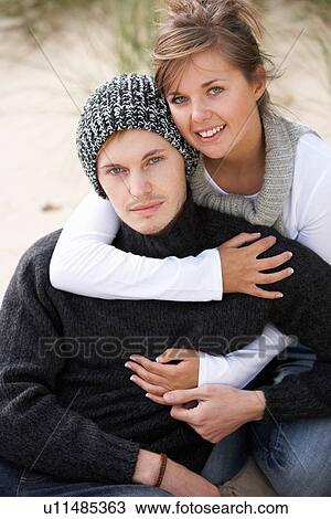 Stock Image - Young Romantic Couple Relaxing On Beach Together. Fotosearch