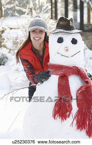 Young Woman Building Snowman In Garden View Large Photo Image Stock Photograph - Young Woman Building Snowman In Garden. Fotosearch