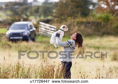Young Woman Outdoors In Autumn Landscape Holding Dog View Large Photo Image Stock Photo - Young Woman Outdoors In Autumn Landscape Holding Dog. Fotosearch