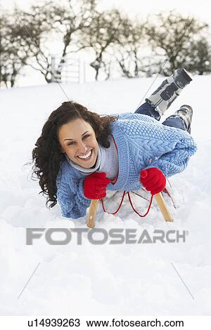 Stock Image - Young Woman Riding On Sledge In Snowy Landscape. Fotosearch