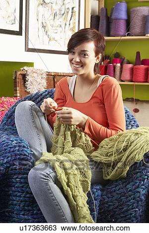 Stock Image - Young Woman Sitting In Chair Knitting. Fotosearch