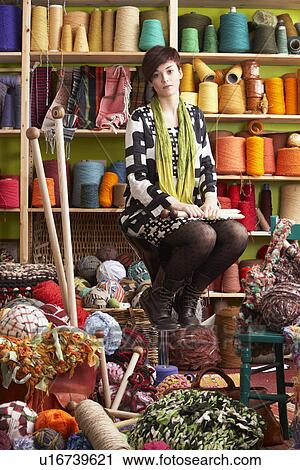 Young Woman Sitting On Stool Holding Knitting Needles In Front Of Yarn Display View Large Photo Image Stock Image - Young Woman Sitting On Stool Holding Knitting Needles In Front Of Yarn Display. Fotosearch