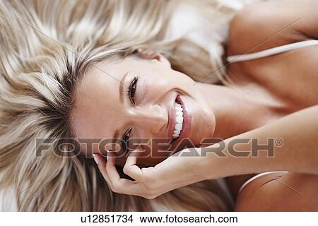 Picture - Blonde woman lying on bed. Fotosearch