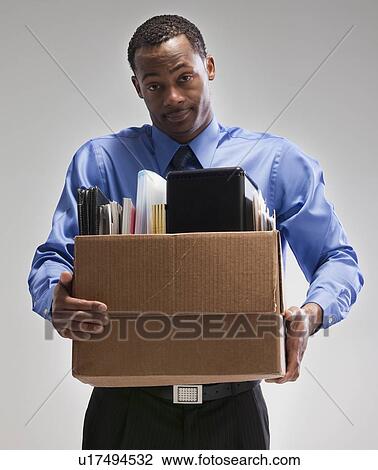 Stock Image - Businessman holding a box of office supplies. Fotosearch