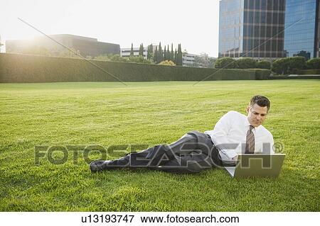 Stock Photo - Businessman relaxing with laptop on lawn. Fotosearch