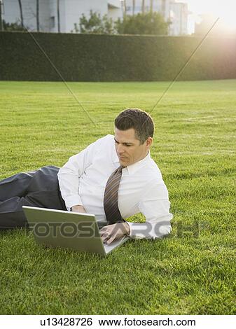 Stock Photograph - Businessman relaxing with laptop on lawn. Fotosearch