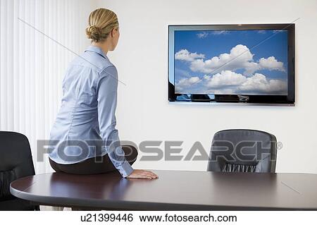 Stock Photograph - Businesswoman sitting on conference table. Fotosearch