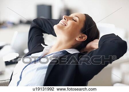 Stock Image - Businesswoman stretching at desk. Fotosearch