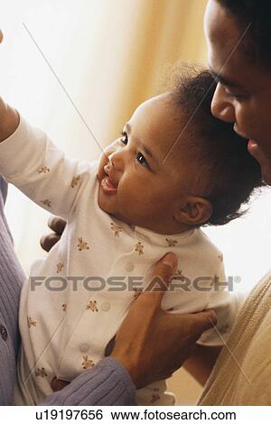 Close-up of mother and father holding their baby View Large Photo Image Stock Photograph - Close-up of mother and father holding their baby. Fotosearch