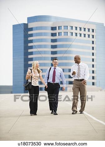 Stock Image - Co-workers walking in parking lot. Fotosearch