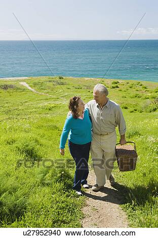 Couple carrying picnic basket to the beach View Large Photo Image Stock Image - Couple carrying picnic basket to the beach. Fotosearch