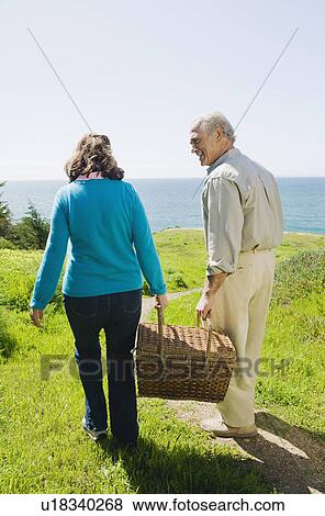Couple carrying picnic basket to the beach View Large Photo Image Stock Photo - Couple carrying picnic basket to the beach. Fotosearch