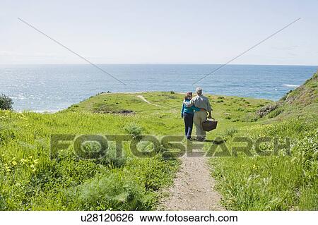 Couple carrying picnic basket to the beach View Large Photo Image Stock Photograph - Couple carrying picnic basket to the beach. Fotosearch