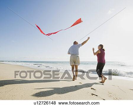 Couple flying kite on beach View Large Photo Image Stock Photo - Couple flying kite on beach. Fotosearch