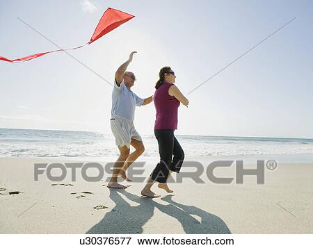 Couple flying kite on beach View Large Photo Image Stock Photo - Couple flying kite on beach. Fotosearch