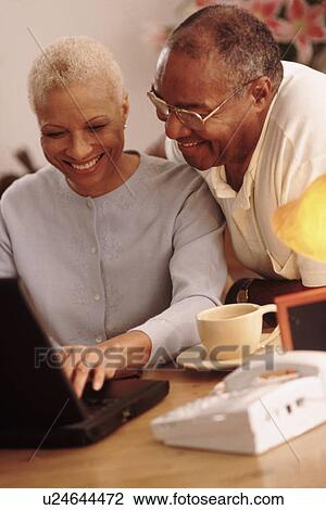 Stock Image - Couple looking at a laptop together. Fotosearch