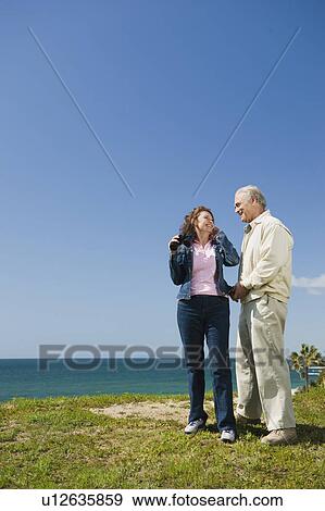 Stock Photo - Couple looking at ocean with binoculars. Fotosearch