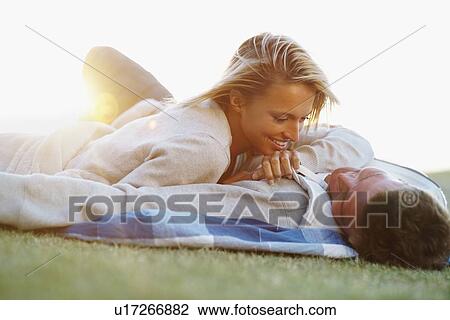 Stock Image - Couple lying down on picnic blanket. Fotosearch