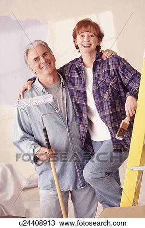 Stock Image - Couple painting the walls in their home. Fotosearch