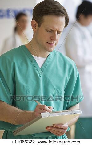Stock Image - Doctor writing on chart. Fotosearch