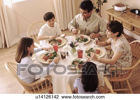 Stock Image - Family eating dinner together. Fotosearch