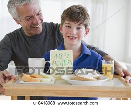 Stock Photo - Father and son bring mom breakfast in bed. Fotosearch