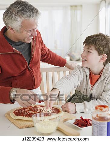 Stock Image - Father and son making pizza. Fotosearch