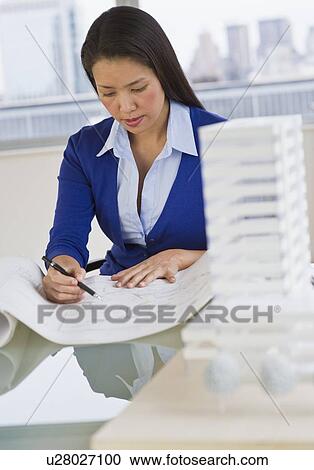 Stock Image - Female architect looking at blueprints. Fotosearch