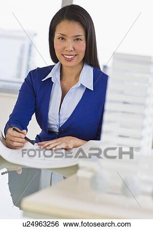 Stock Photograph - Female architect looking at blueprints. Fotosearch
