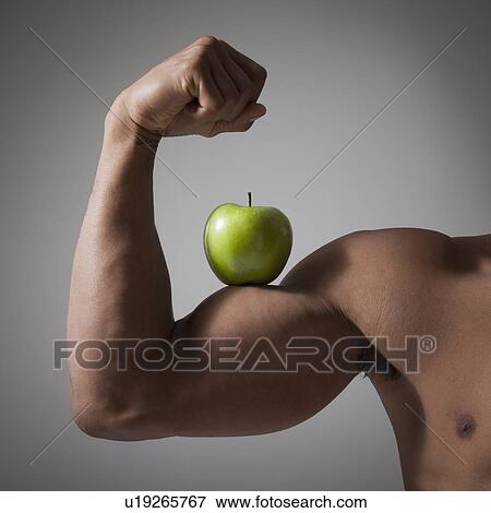 Stock Photo - Green apple perched on a flexed muscular arm. Fotosearch