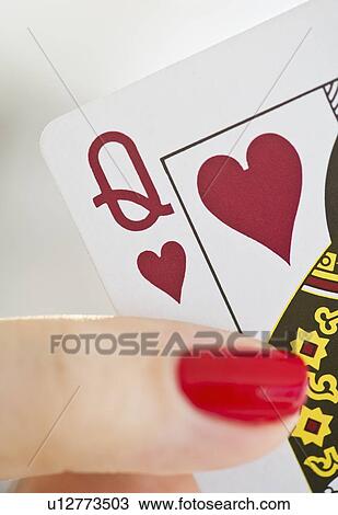 Stock Image - Hand holding a queen of hearts card. Fotosearch