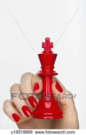 Stock Photo - Hand holding red king chess piece. Fotosearch