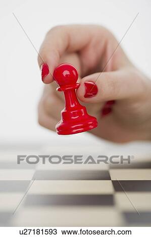 Stock Image - Hand holding red pawn chess piece. Fotosearch