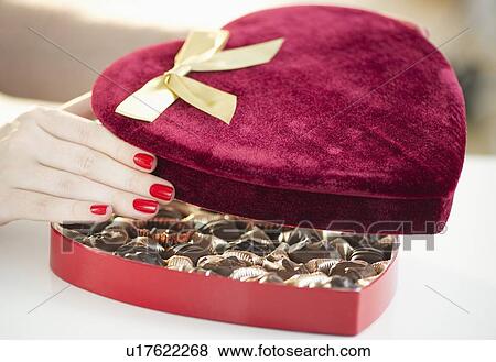 Stock Photo - Hand opening a velvet heart shaped box of chocolates. Fotosearch