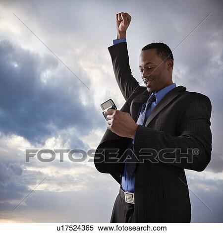Stock Photography - Happy businessman holding a mobile phone. Fotosearch