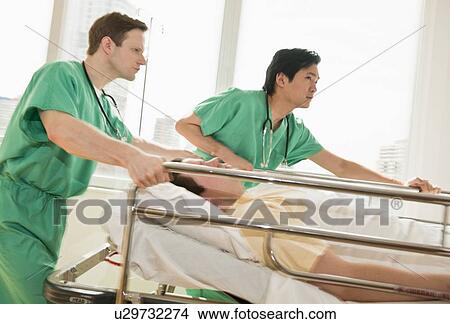 Healthcare workers pushing gurney in emergency room View Large Photo Image Picture - Healthcare workers pushing gurney in emergency room. Fotosearch