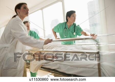 Healthcare workers pushing gurney in emergency room View Large Photo Image Stock Image - Healthcare workers pushing gurney in emergency room. Fotosearch