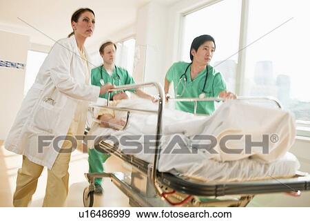 Healthcare workers pushing gurney in emergency room View Large Photo Image Stock Photo - Healthcare workers pushing gurney in emergency room. Fotosearch
