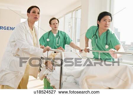 Healthcare workers pushing gurney in emergency room View Large Photo Image Stock Photo - Healthcare workers pushing gurney in emergency room. Fotosearch