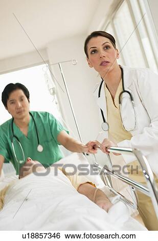 Stock Photograph - Healthcare workers pushing gurney in emergency room. Fotosearch