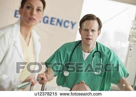 Stock Photography - Healthcare workers pushing gurney in emergency room. Fotosearch