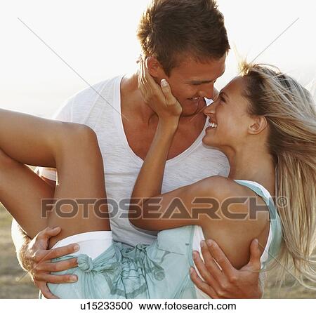 Stock Image - Man carrying girlfriend. Fotosearch