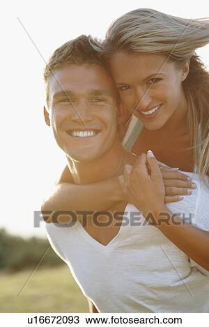 Stock Image - Man giving girlfriend a piggy back ride. Fotosearch